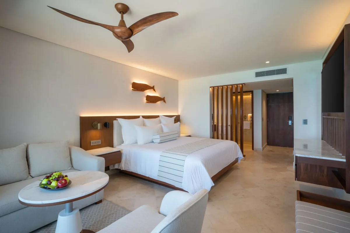 Deluxe Ocean View Balcony suite with king bed and seating area at Secrets Mirabel Cancun Resort & Spa.