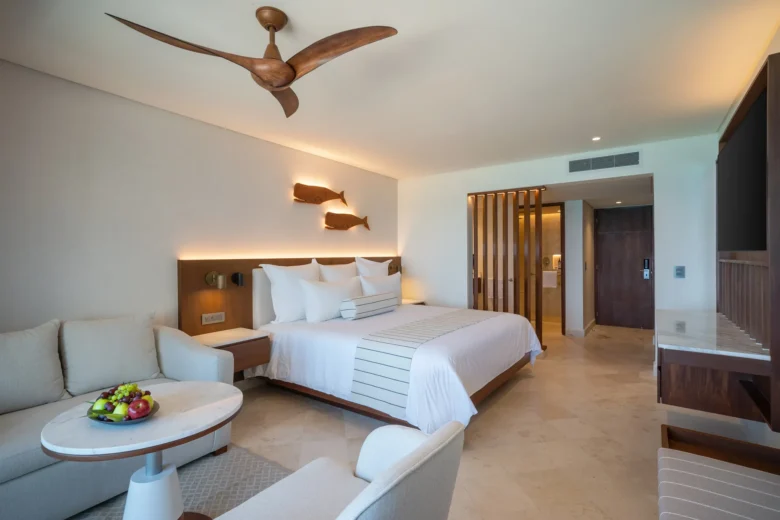 Deluxe Ocean View Balcony suite with king bed and seating area at Secrets Mirabel Cancun Resort & Spa.
